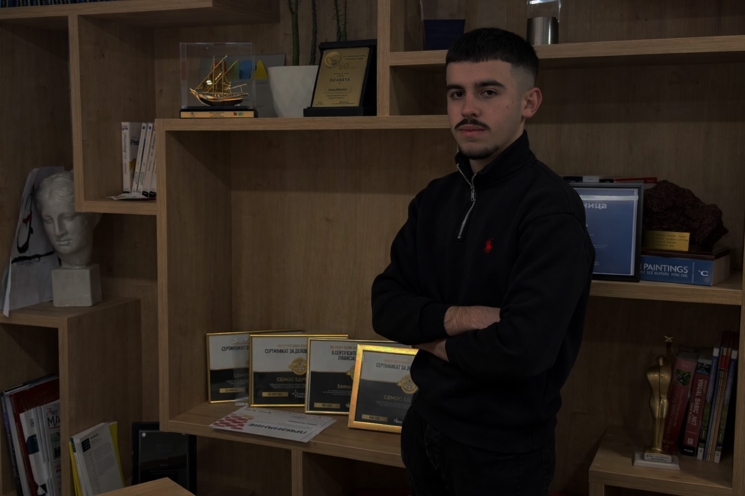Mahir Sabotic standing in front of an award shelf